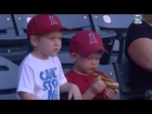 Kid struggles to eat a hot dog at baseball game